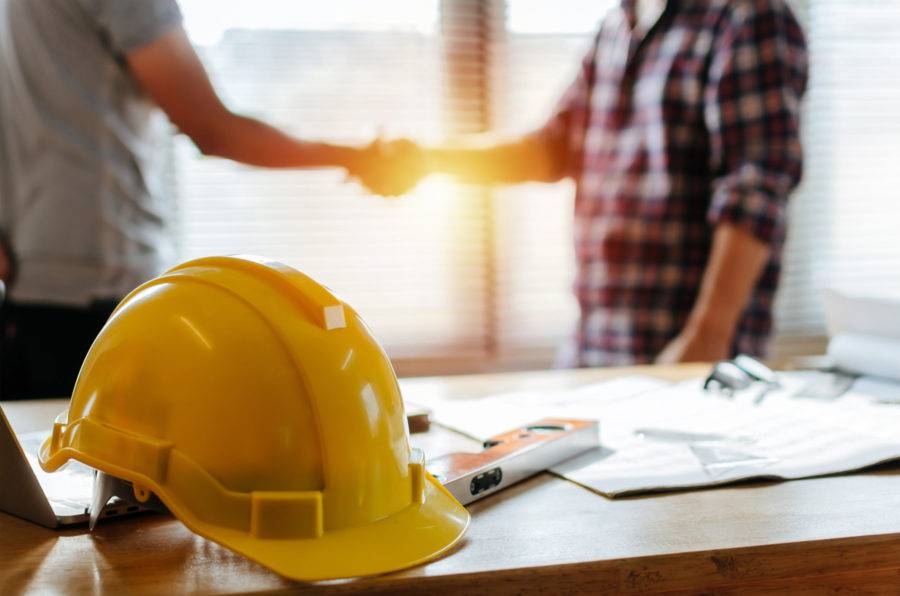 Yellow Safety Helmet On Workplace Desk With Construction Worker